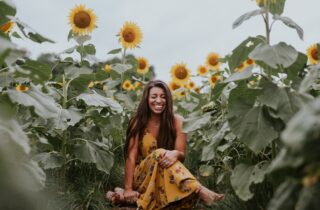 woman smiling in a field of sunflowers | dentistaltamonte.com